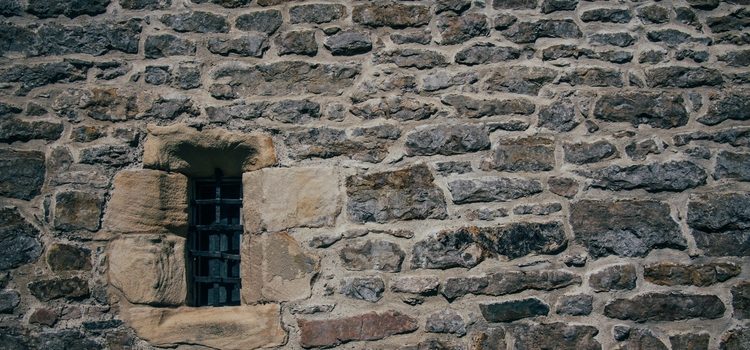 Beautiful shot of a stone brick old structure with a blocked small window A beautiful shot of a stone brick old structure with a blocked small window